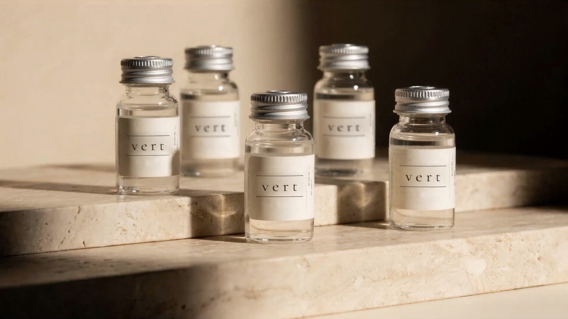 Five VERT research peptide vials on a travertine ledge as afternoon light drifts across them
